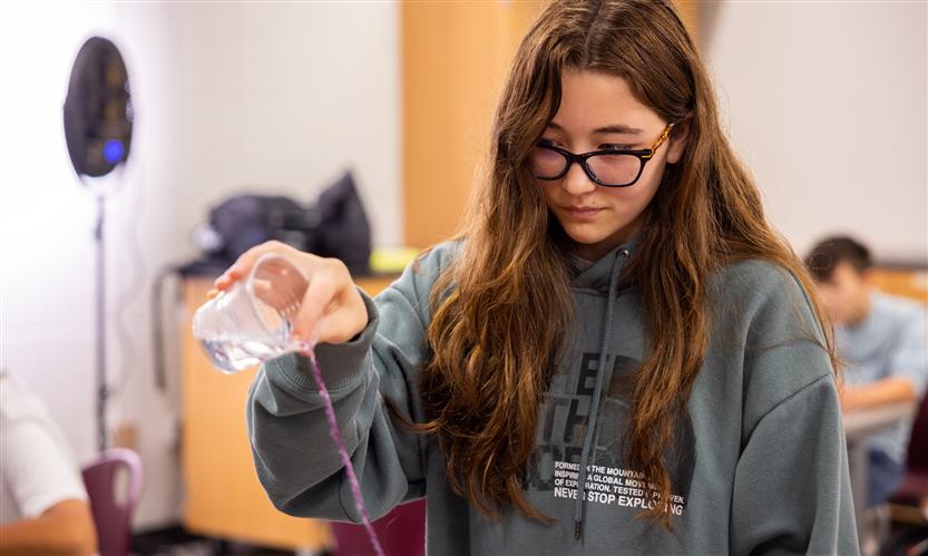 A girl pours water down a string
